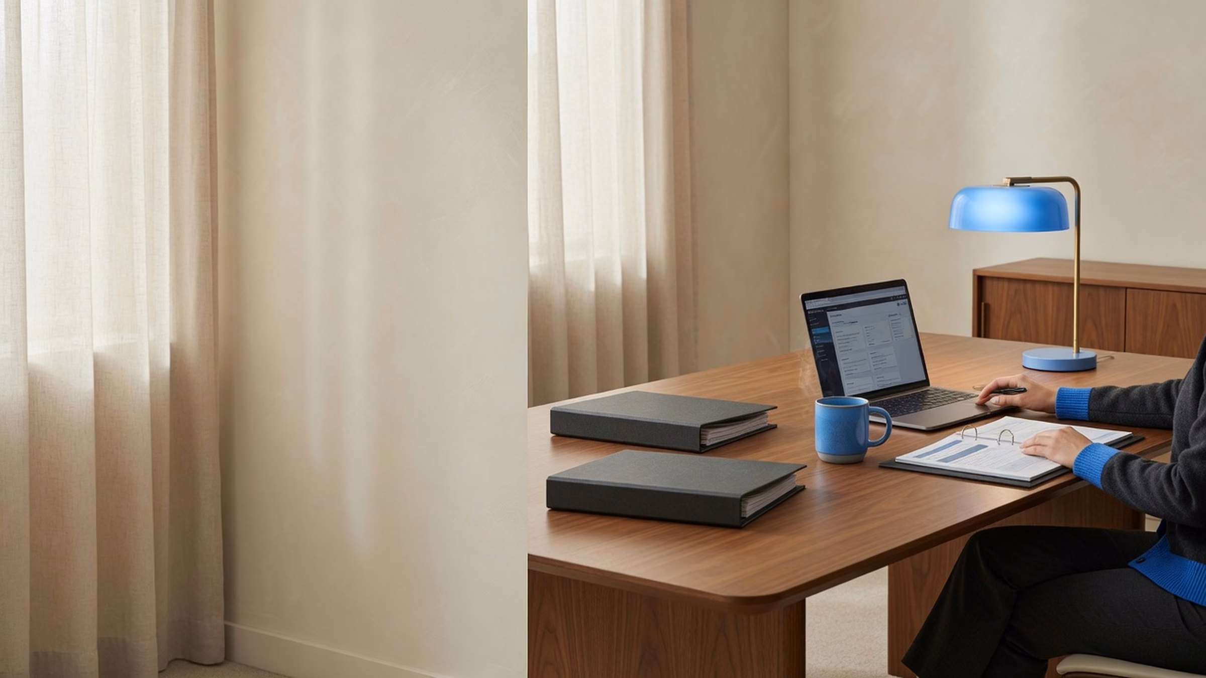 Wide walnut conference table with unmarked binders and a laptop showing illegible dense UI; person mid-task in charcoal with #1B6BB5 knit/cuffs and blue lamp; cream plaster and linen; left third calm